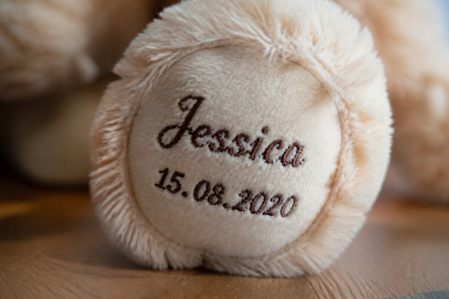 Fußsohle eines hellen Teddybären mit einem in dunklem Garn gestickten Vornamen und einem Datum